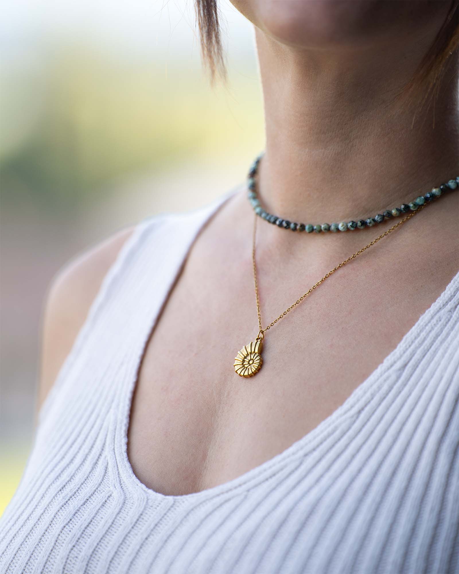 Frau trägt Halksette Gold mit Ammonit Anhänger und Naturstein Choker